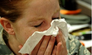 Woman sneezing into tissue